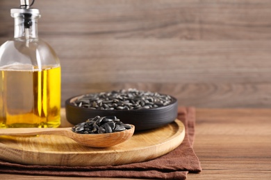 Photo of Sunflower seeds and oil on wooden table. Space for text