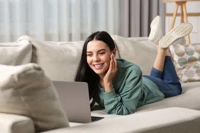 Photo of Happy woman working with laptop on sofa at home