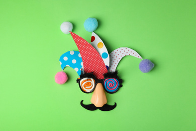 Photo of Funny face made of party items on green background, flat lay. April Fool's Day