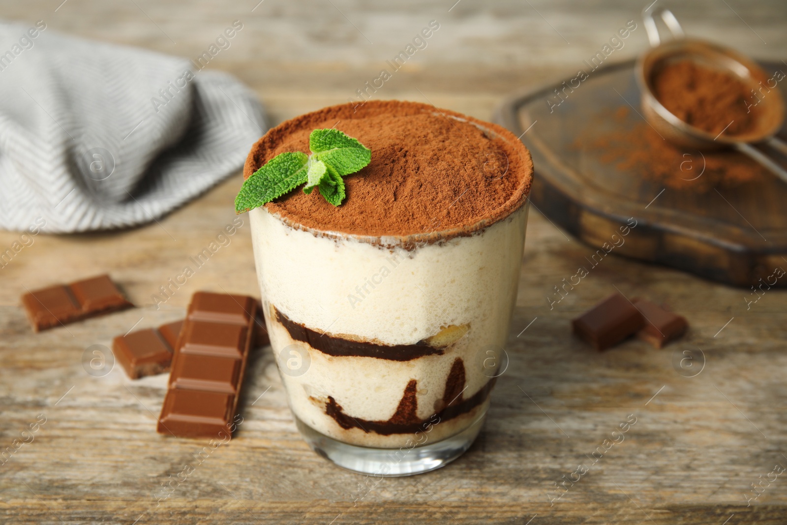 Photo of Glass of tiramisu cake and chocolate on wooden table