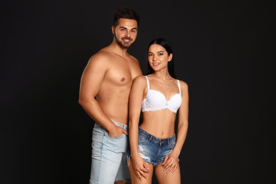 Photo of Young woman in underwear and denim shorts with her boyfriend on black background