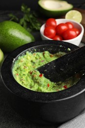 Photo of Mortar with delicious guacamole and ingredients on table