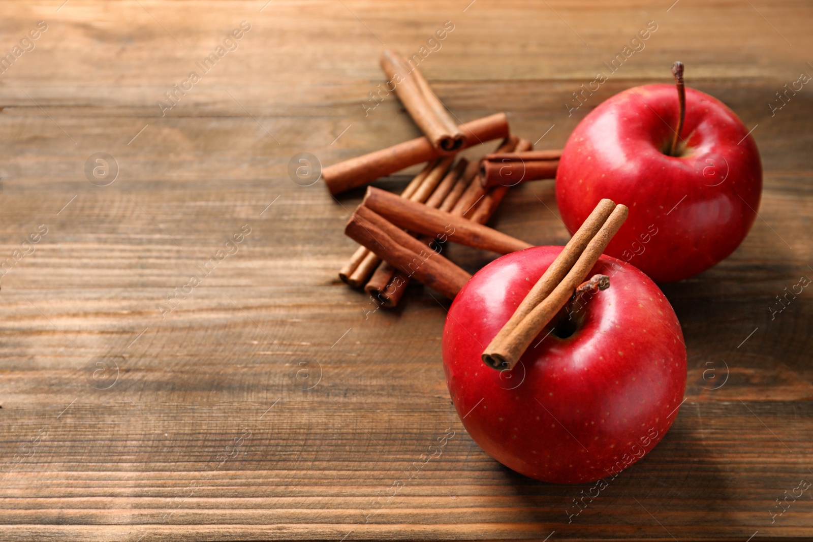 Photo of Fresh apples and cinnamon sticks on wooden table