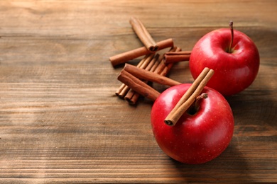 Fresh apples and cinnamon sticks on wooden table