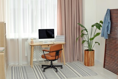 Stylish teenager's room interior with workplace and beautiful houseplant