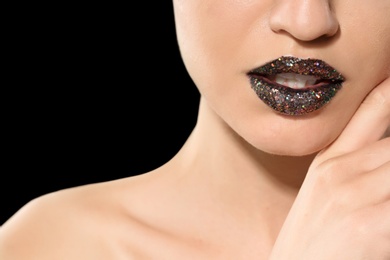 Beautiful young model with creative lips makeup on black background
