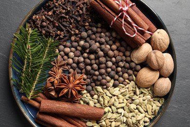 Different spices, nuts and fir branches on dark gray table, top view