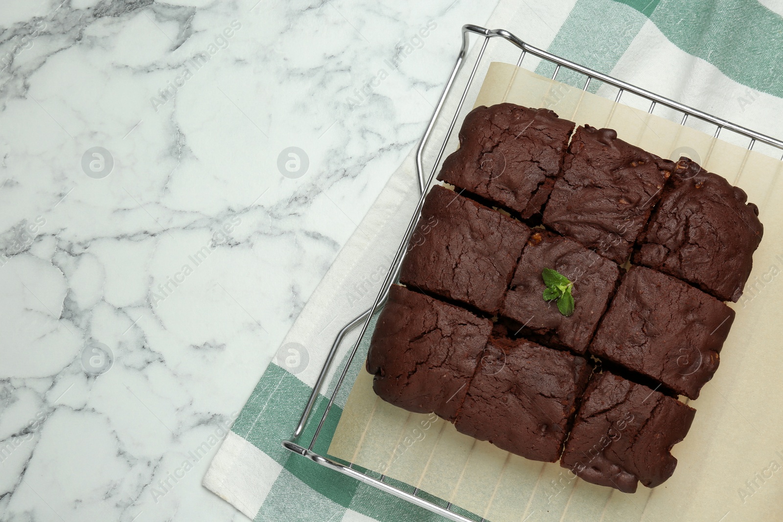 Photo of Delicious freshly baked brownies on white marble table, top view. Space for text