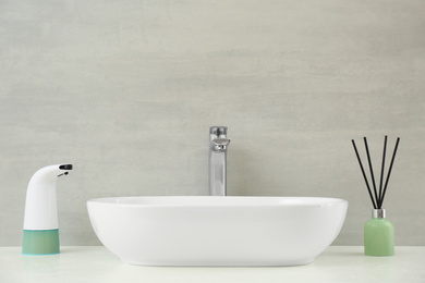 Photo of Modern automatic soap dispenser near sink in bathroom