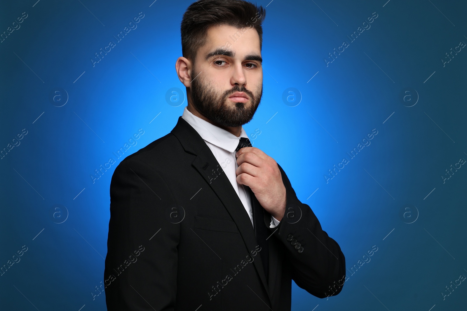 Photo of Handsome businessman in suit and necktie on blue background