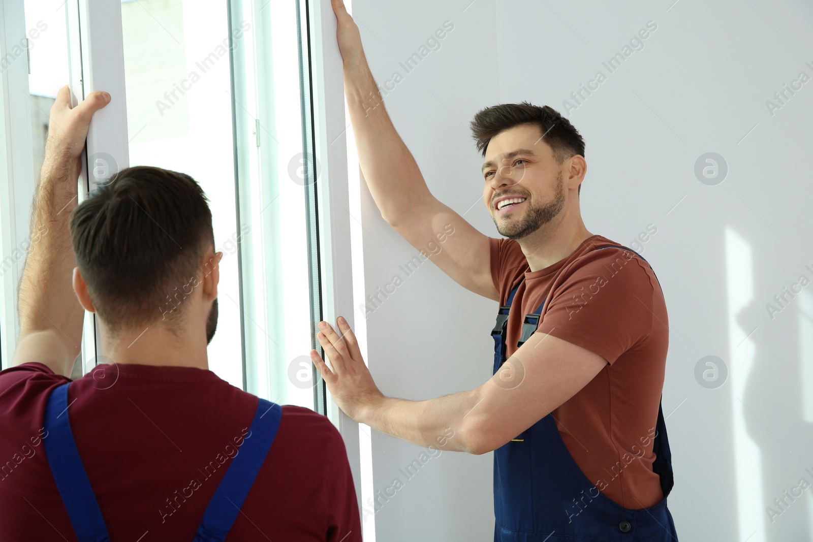 Photo of Construction workers installing plastic window in house