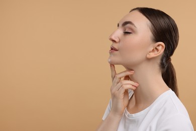 Photo of Beautiful woman touching her chin on beige background. Space for text
