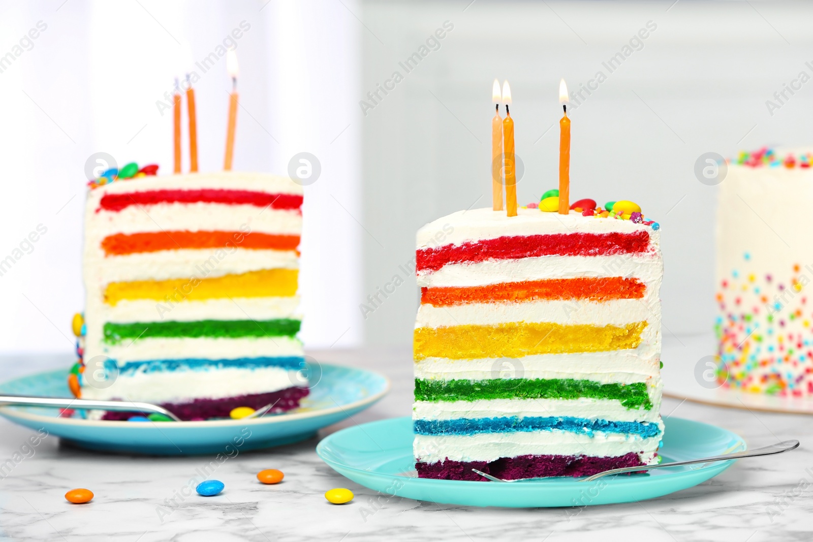 Photo of Delicious rainbow cake with candles for party on table