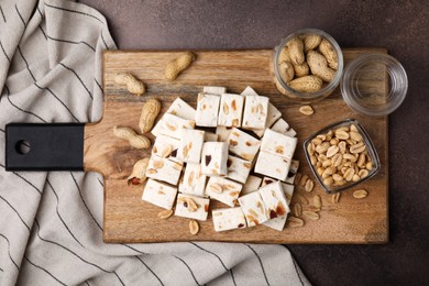 Pieces of delicious nutty nougat on brown table, top view