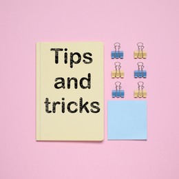 Image of Notebook with text Tips and tricks on pink background, flat lay