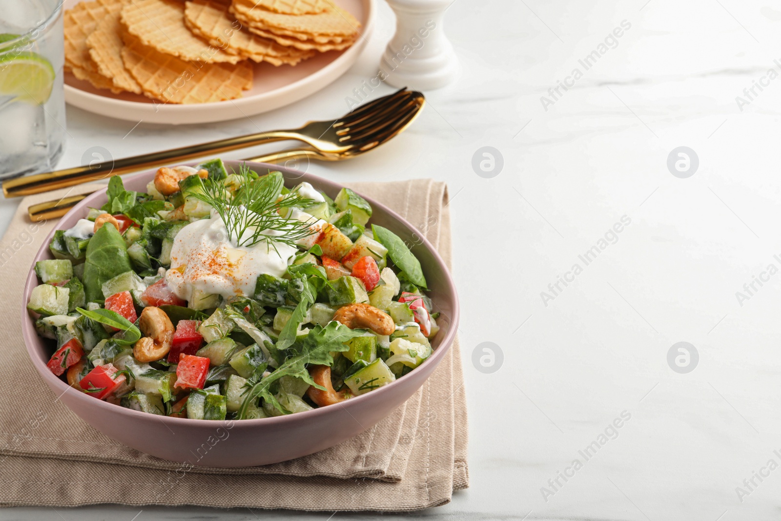 Photo of Bowl of delicious cucumber salad served on white marble table. Space for text