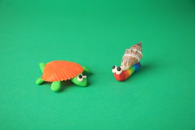 Photo of Turtle and snail made from plasticine on green background. Children's handmade ideas