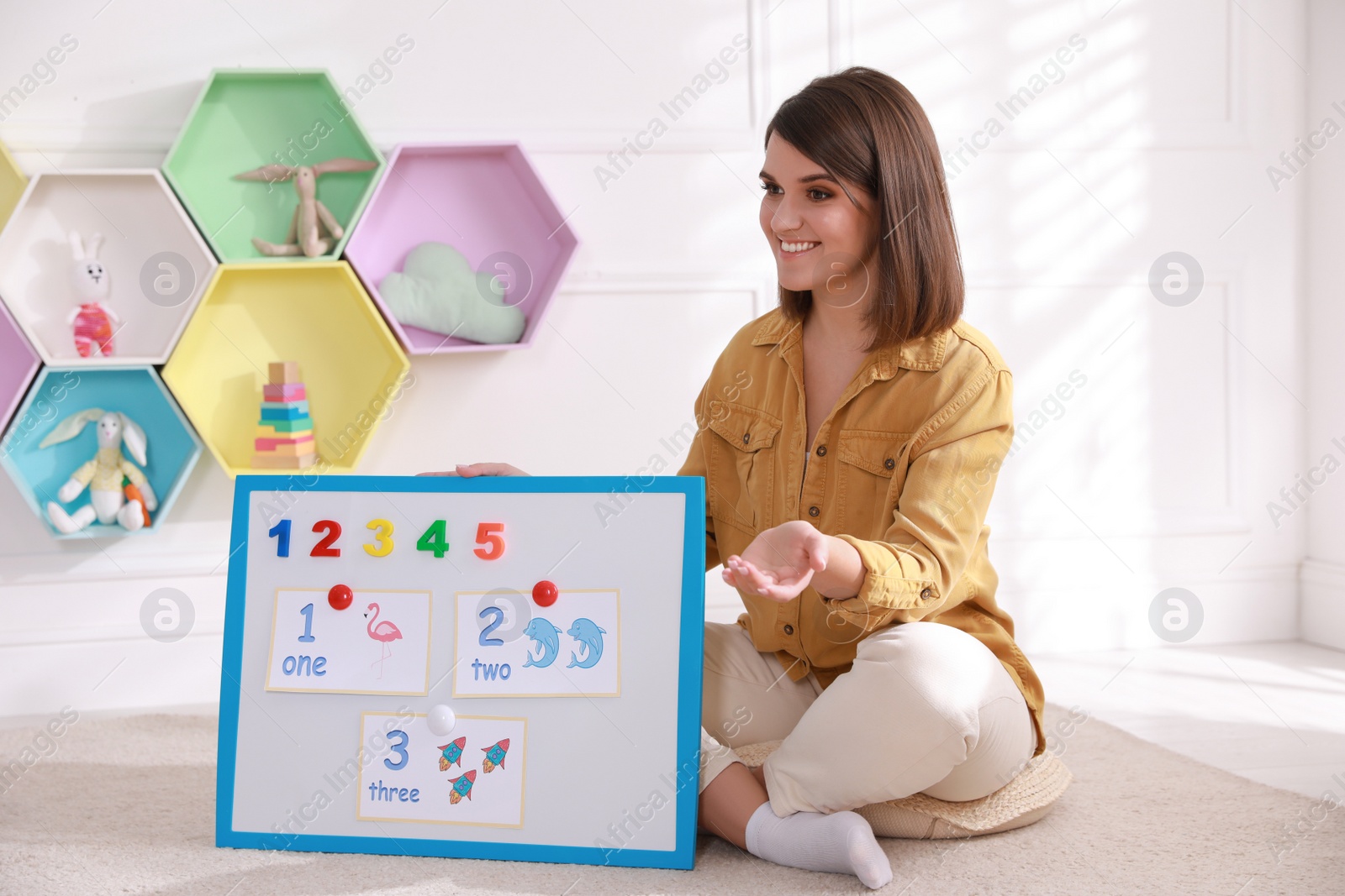 Photo of Happy female English teacher giving lesson indoors. Early childhood education