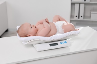 Photo of Cute little baby lying on scales in clinic