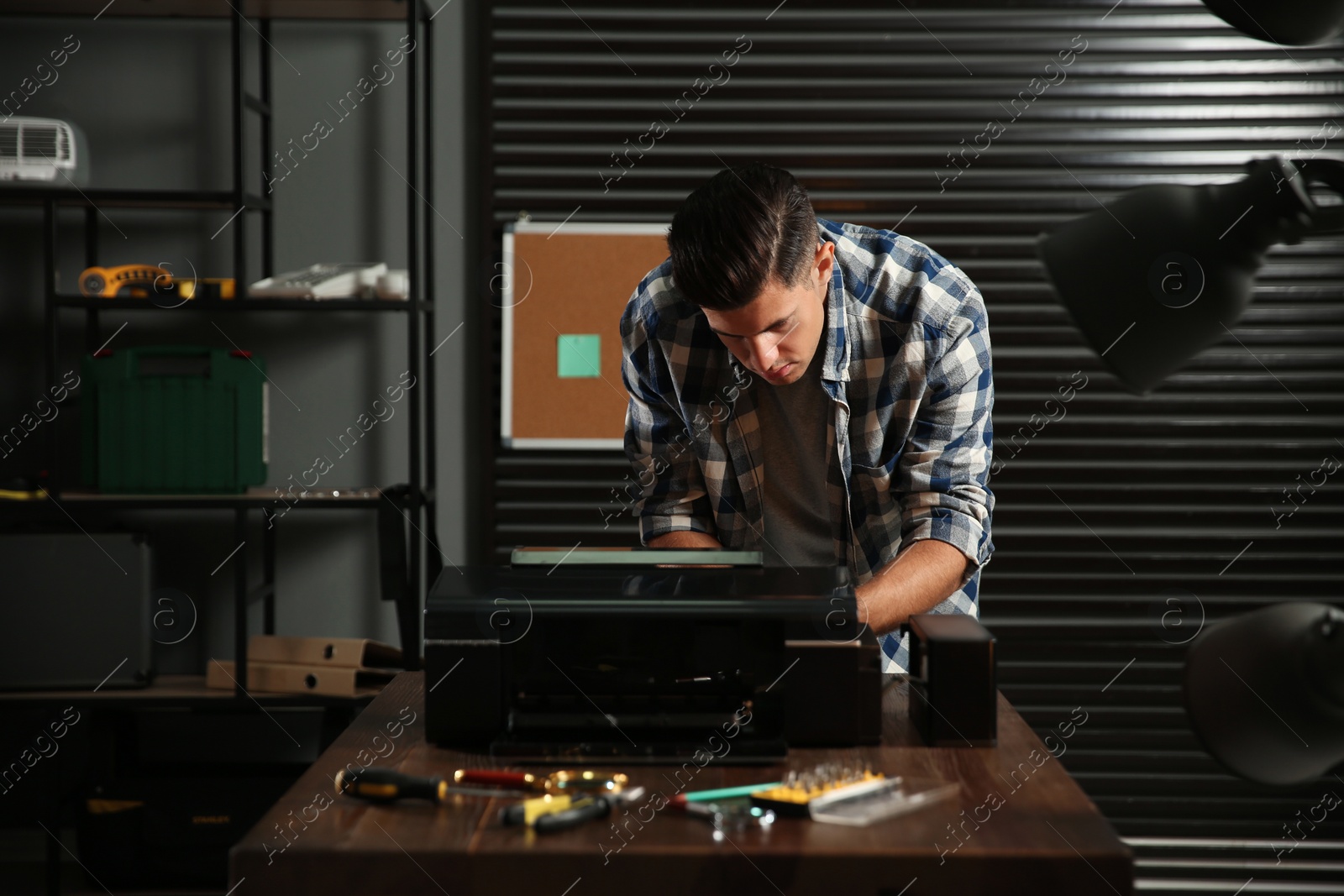 Photo of Professional repairman fixing modern printer in office