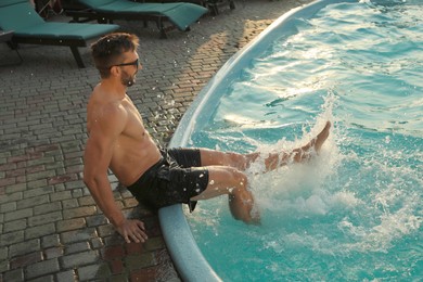 Happy man having fun near outdoor swimming pool on summer day