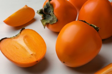 Photo of Delicious ripe juicy persimmons on white table