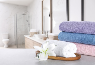 Image of Fresh towels and lily flower on light grey marble table in bathroom. Space for text