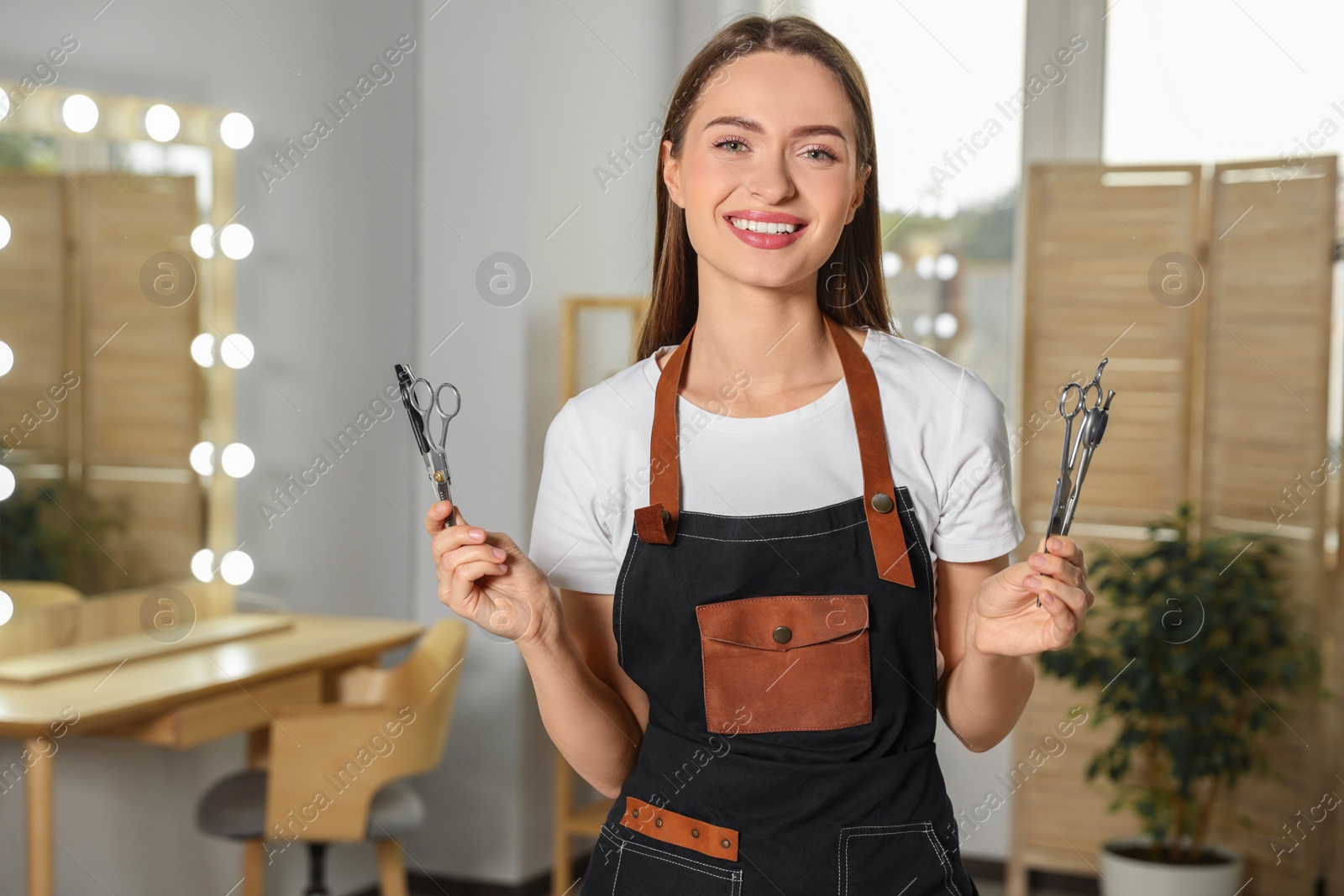 Photo of Portrait of happy hairdresser with professional scissors in beauty salon