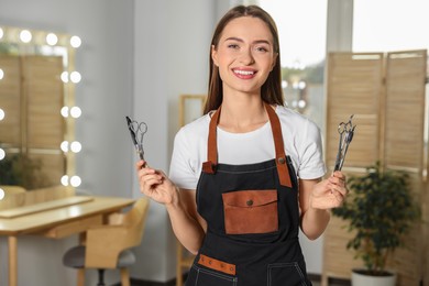 Portrait of happy hairdresser with professional scissors in beauty salon