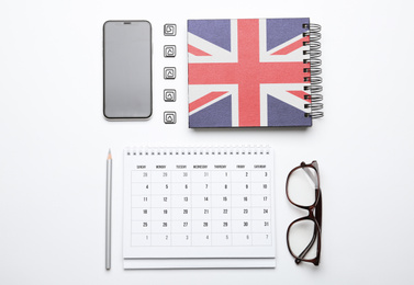 Calendar, notebook, glasses and mobile phone on white background, top view. Learning English