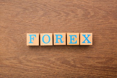Photo of Word Forex made of cubes with letters on wooden table, top view