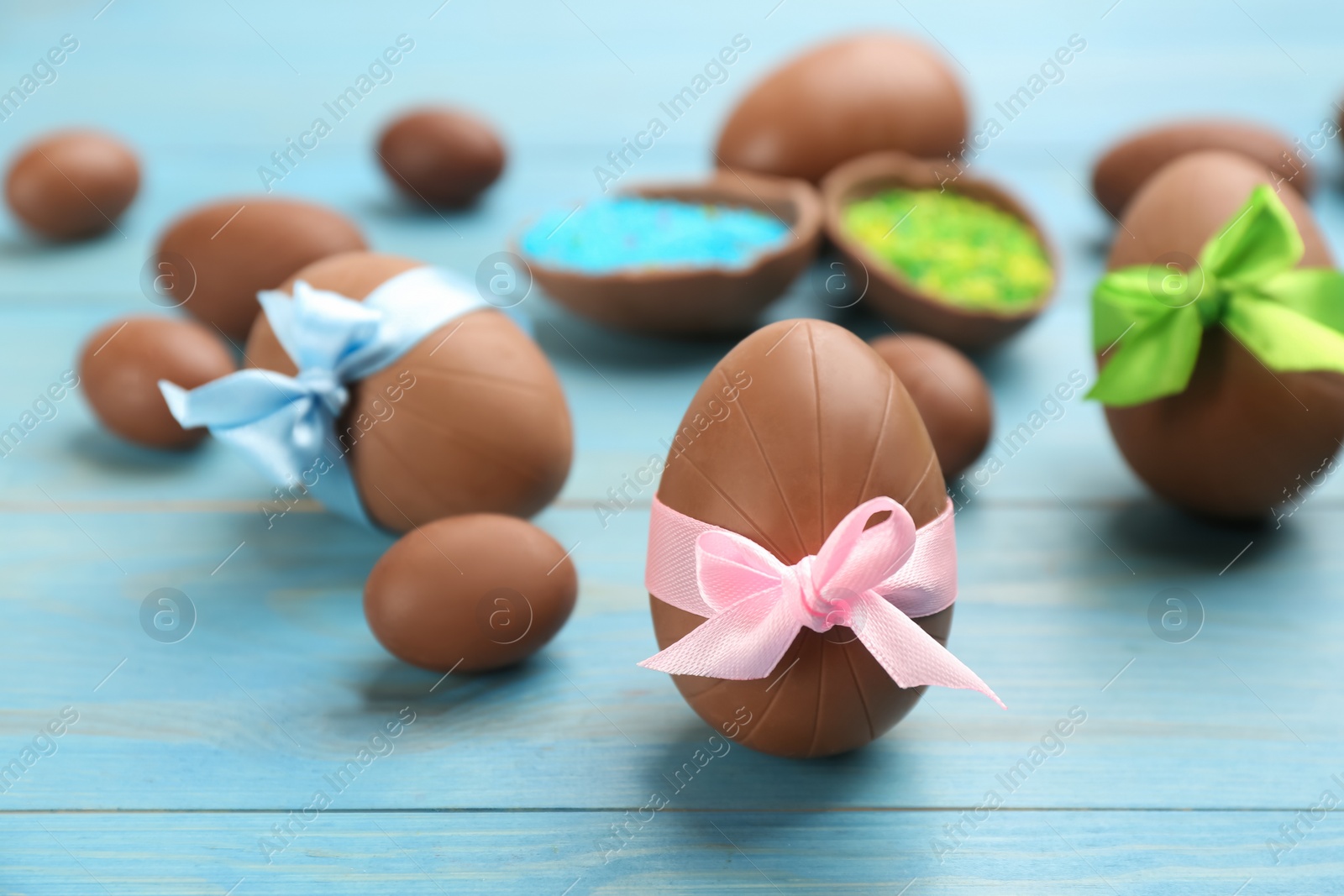 Photo of Sweet chocolate eggs on light blue wooden table