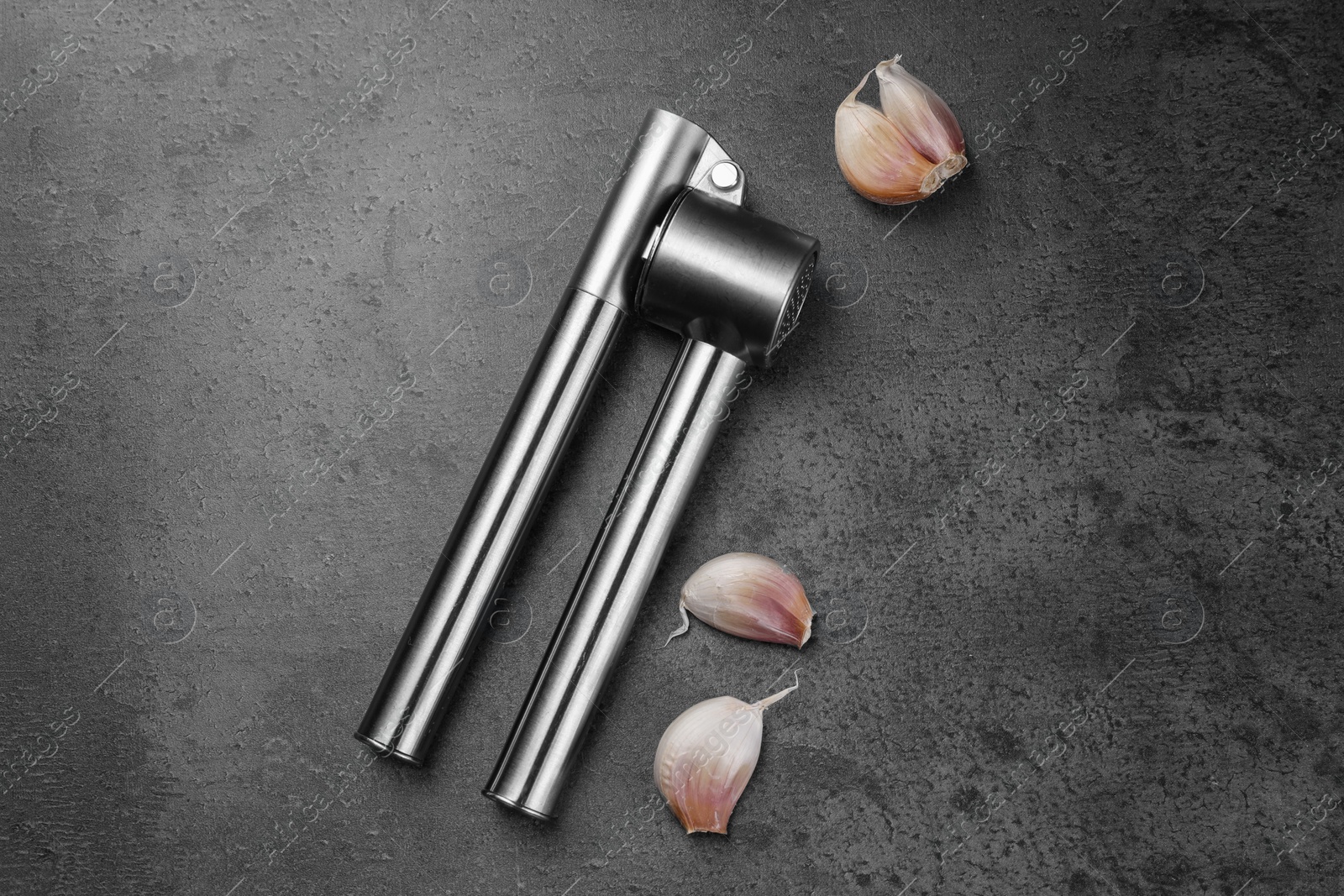 Photo of Garlic press and cloves on grey table, flat lay