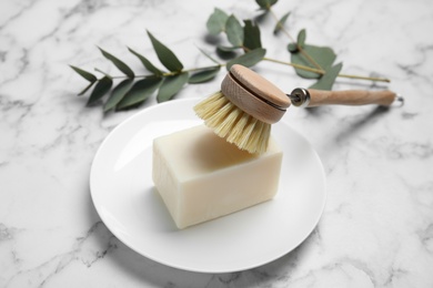 Photo of Cleaning brush and soap bar for dish washing on white marble table