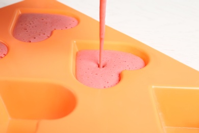 Photo of Pouring smoothie into ice cube tray on table, closeup