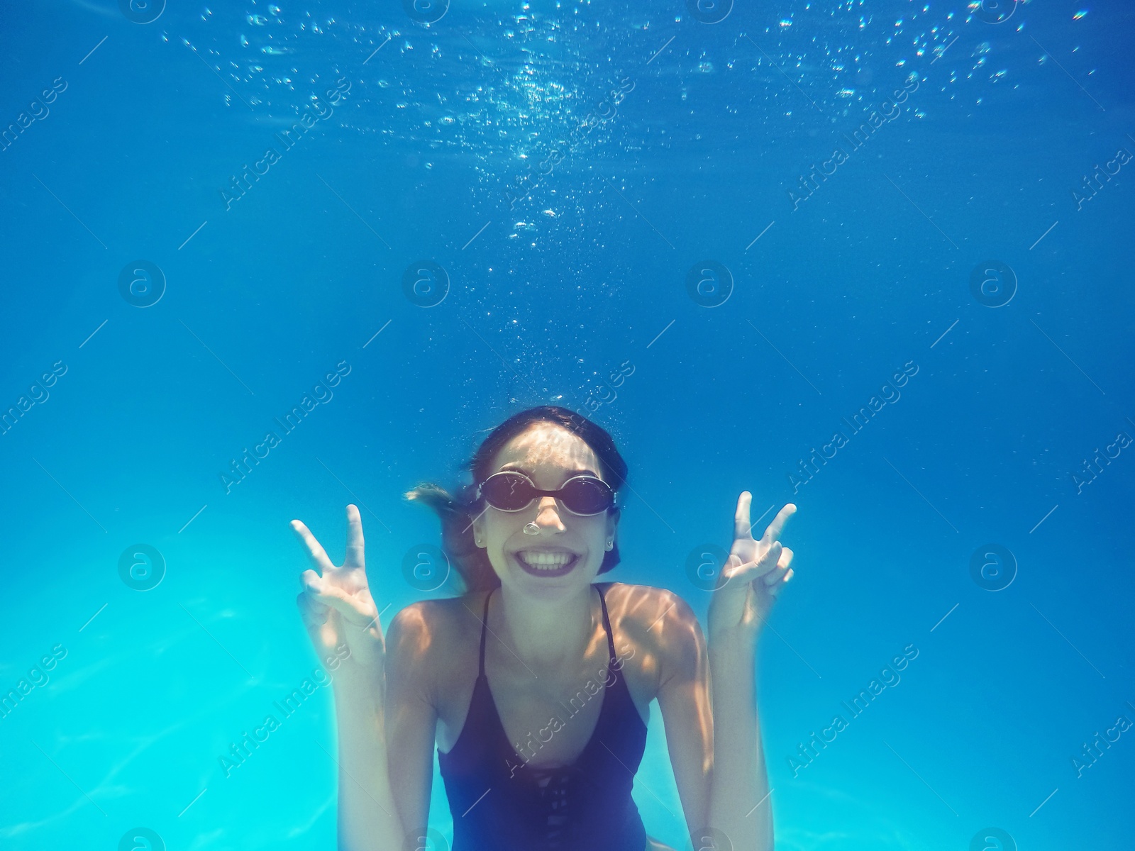 Photo of Beautiful young woman swimming in pool, underwater view