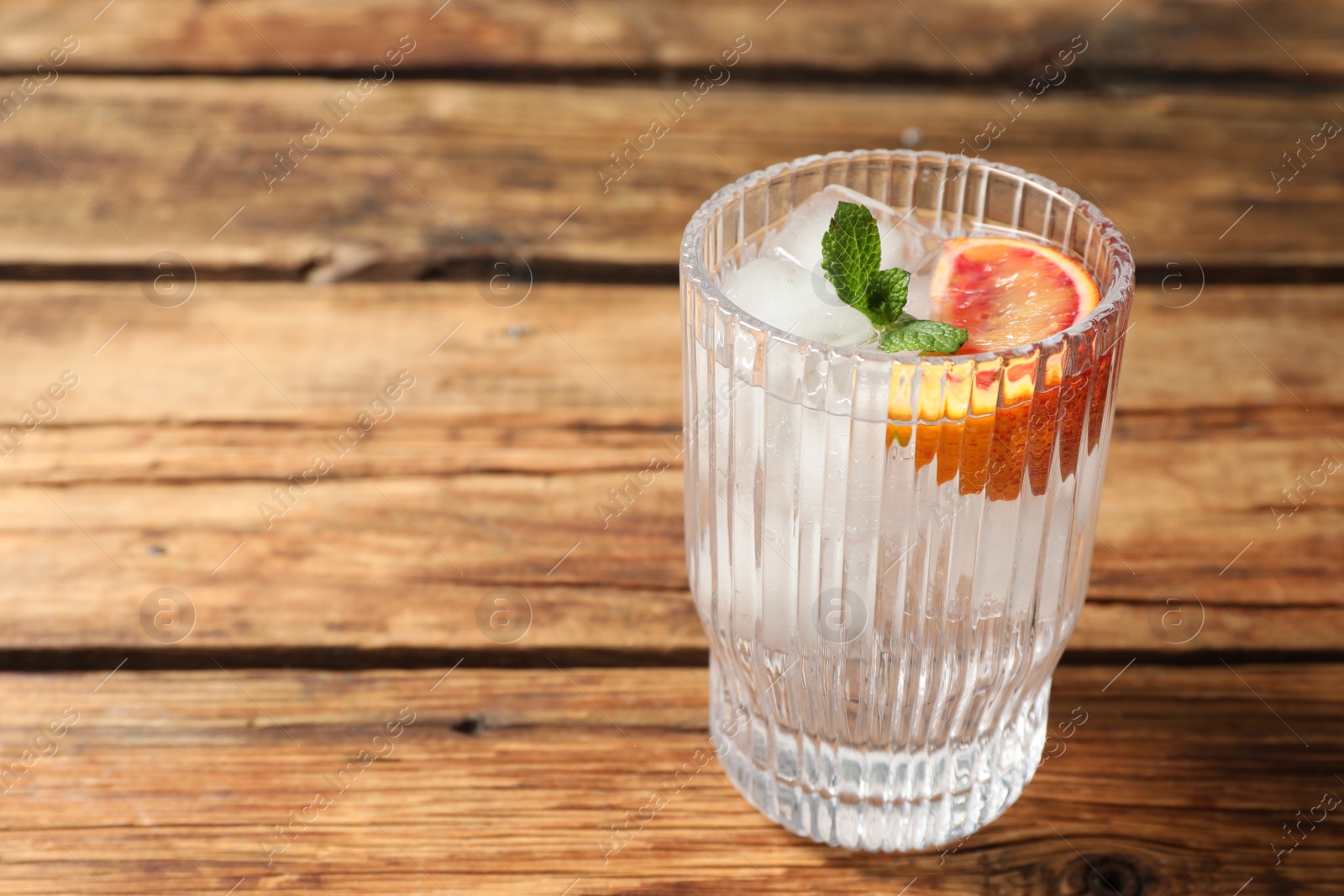 Photo of Delicious refreshing drink with sicilian orange and mint on wooden table. Space for text