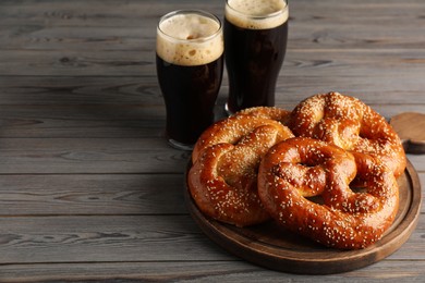 Photo of Tasty pretzels and glasses of beer on wooden table, space for text