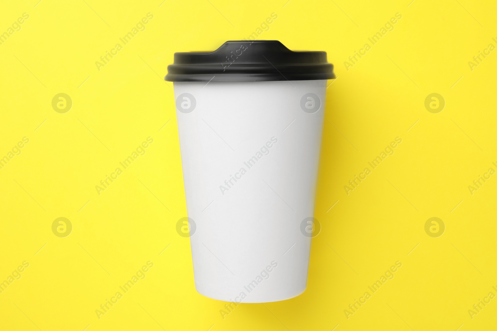 Photo of One paper cup on yellow background, top view. Coffee to go