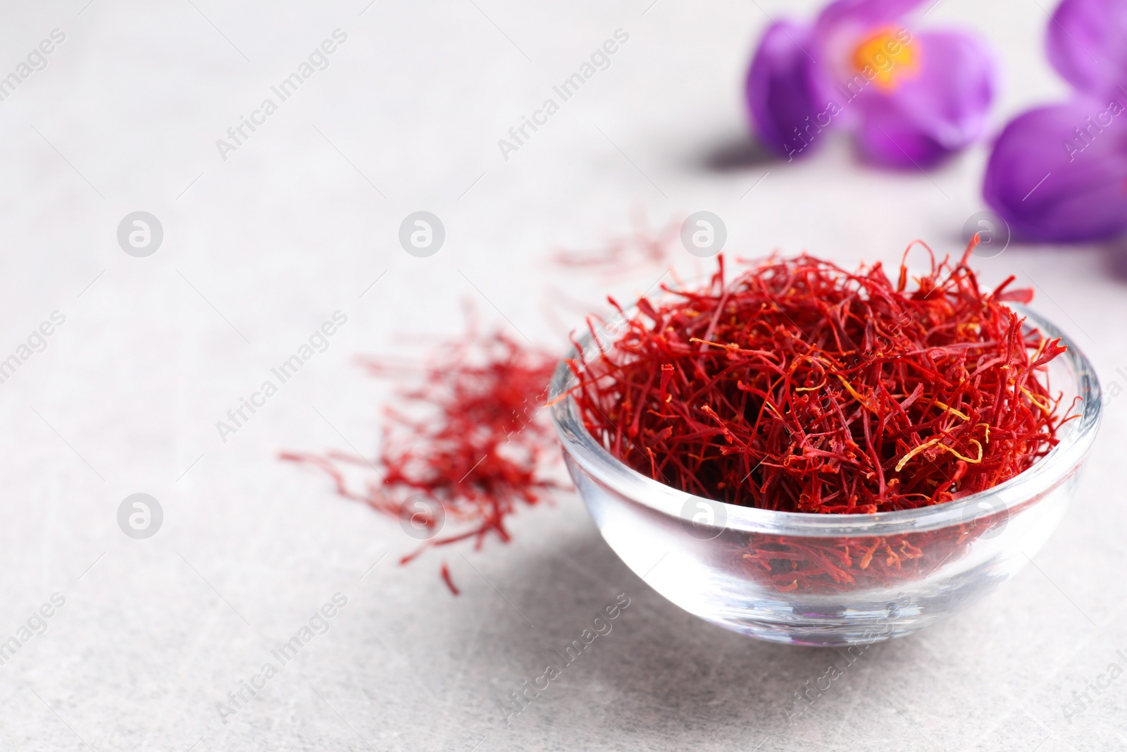 Photo of Dried saffron and crocus flowers on grey table, closeup. Space for text