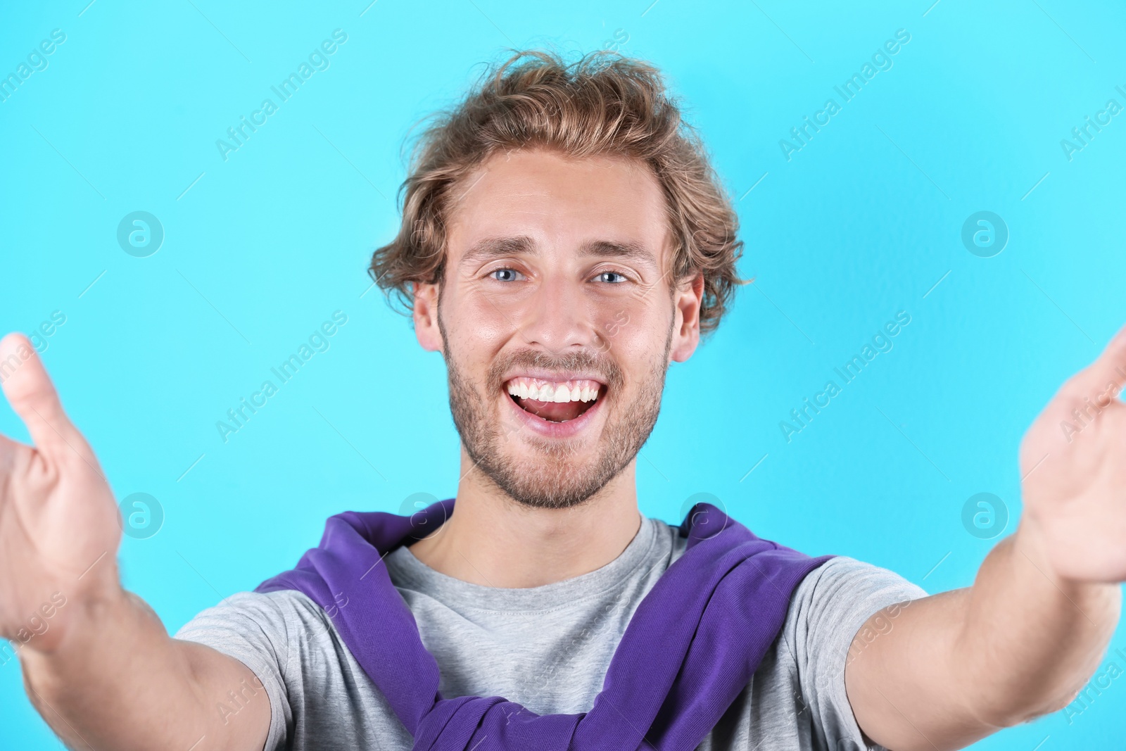 Photo of Handsome young man laughing and taking selfie on color background