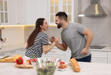 Photo of Happy lovely couple dancing together while cooking in kitchen