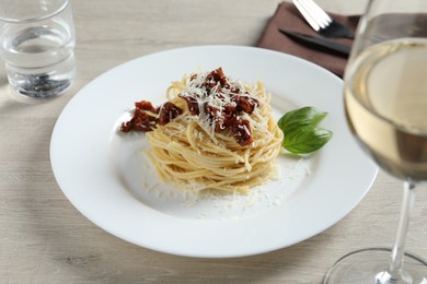 Photo of Tasty spaghetti with sun-dried tomatoes and parmesan cheese served on wooden table, closeup. Exquisite presentation of pasta dish