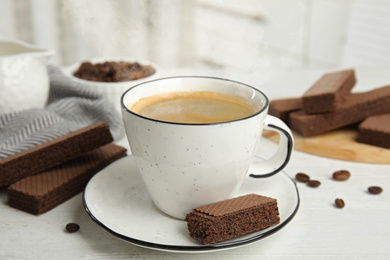 Photo of Delicious wafers and cup of coffee for breakfast on white wooden table