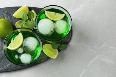 Photo of Delicious cocktails with lime and ice balls on grey table, top view. Space for text