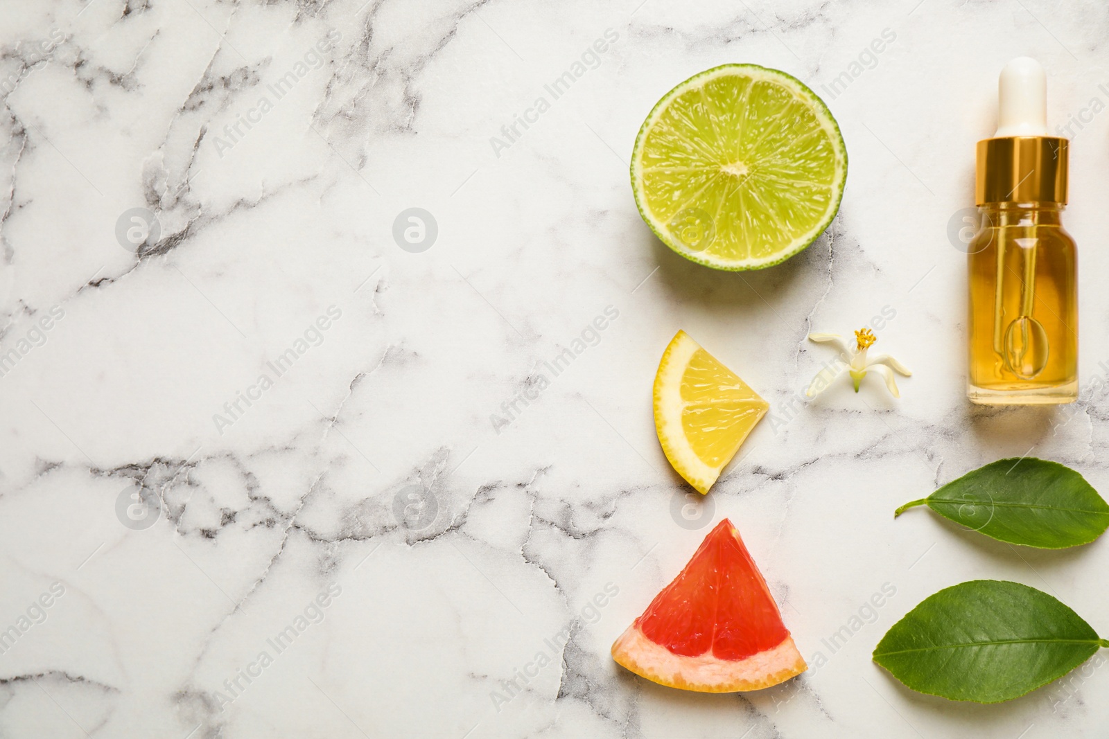 Photo of Flat lay composition with bottle of citrus essential oil on white marble background. Space for text