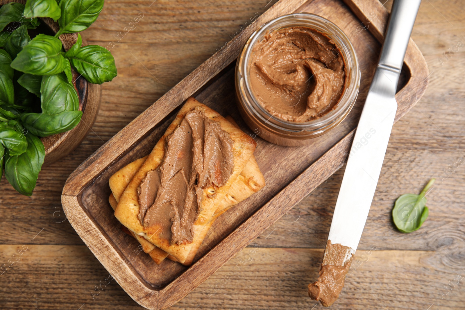 Photo of Crispy crackers with delicious meat pate and knife on wooden table, flat lay