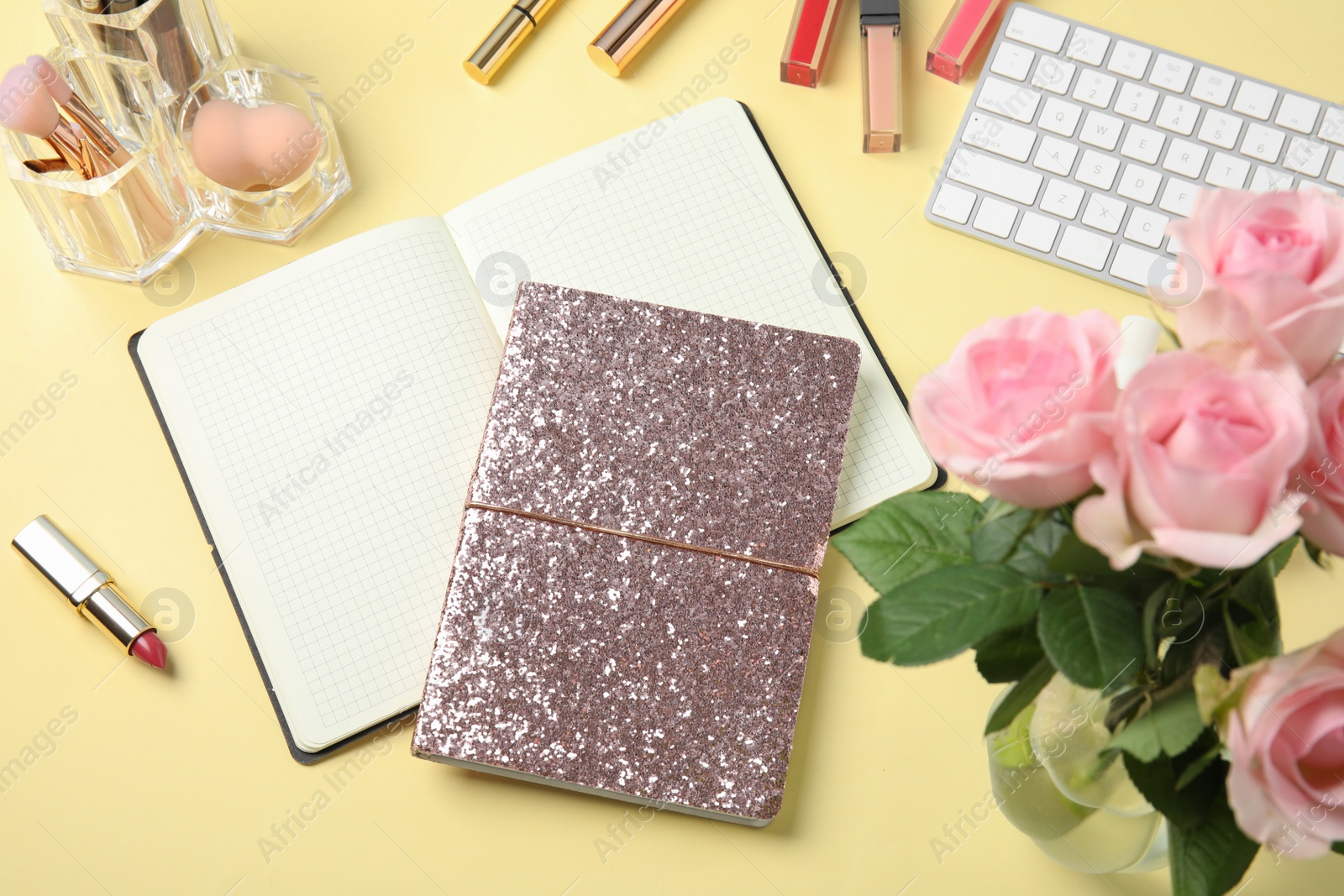 Photo of Blogger's workplace with notebooks, keyboard and cosmetics on color background, flat lay