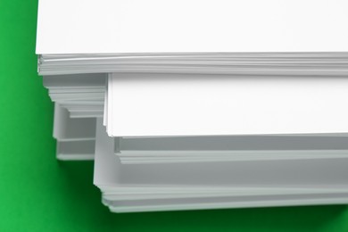 Stack of white paper on green background, closeup