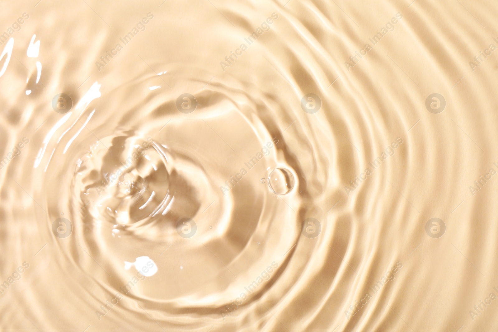 Photo of Closeup view of water with rippled surface on beige background